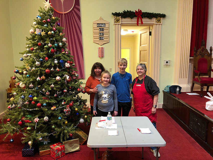 (left to right) First Presbyterian Church members Marge Elkin, Sophia, Daniel, and Heather Benedict next to the church&rsquo;s Christmas tree