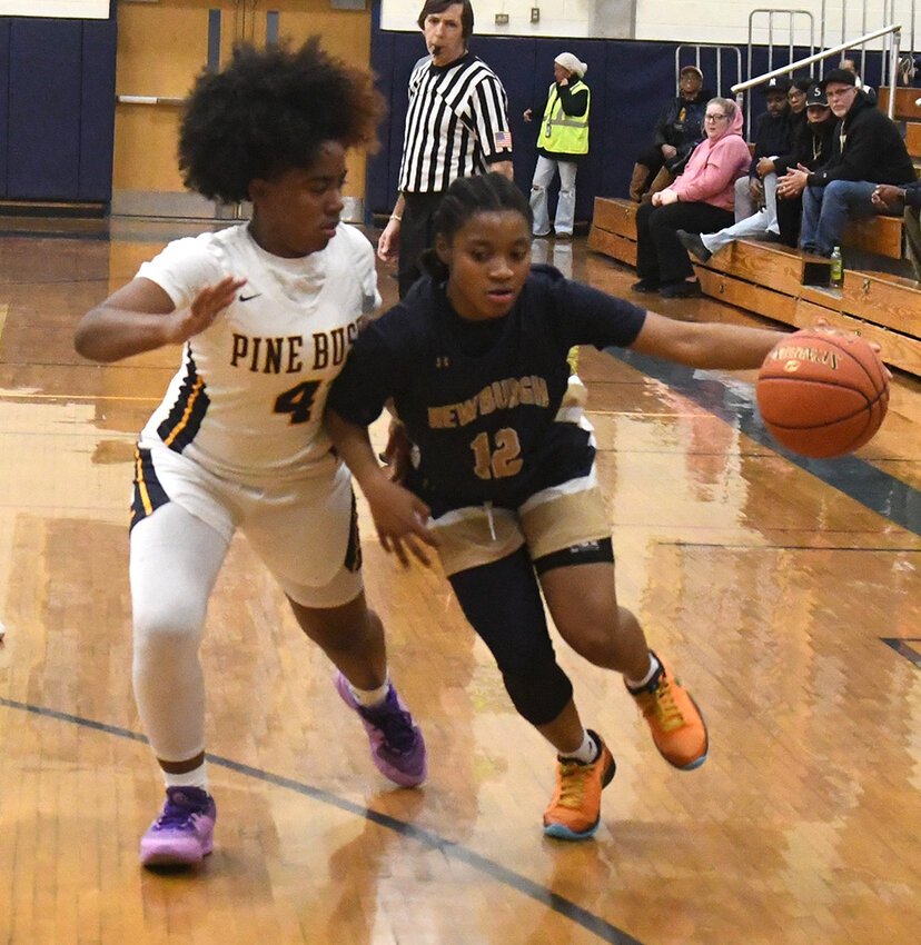 Newburgh’s T.T. Burden drives past Pine Bush’s Jah-esa Stokes during Thursday’s OCIAA Division I girls’ basketball game at Pine Bush High School.