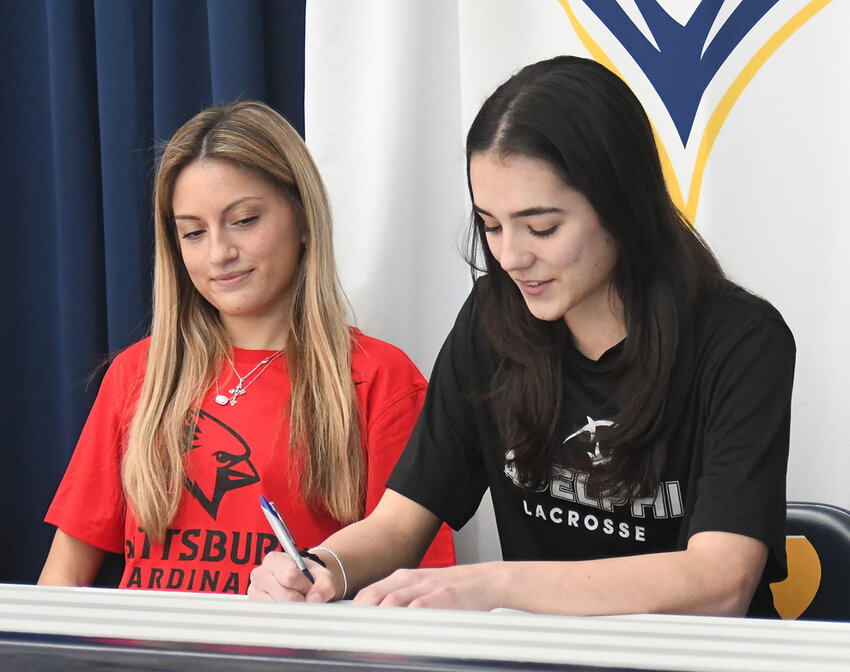 Highland’s Caitlyn Becker signs her commitment to play women’s lacrosse at Adelphi University as her teammate Leah Klotz looks on during Thursday’s signing ceremony at Highland High School.
