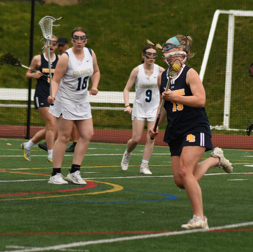 Pine Bush’s Sophia Licardi brings the ball down the field as Newburgh’s Ashley Myers (18) and Megan Torres (9) look on during a girls’ lacrosse game on April 11, 2023, at Academy Field in Newburgh.
