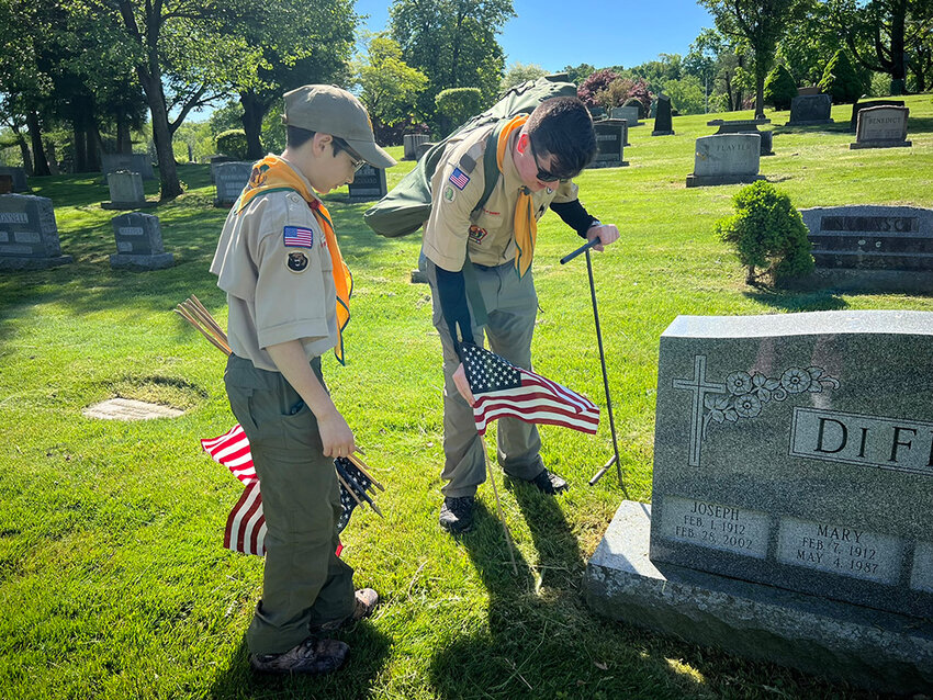 Scouts Jaik Karras(l.)  and Ryan Sita place flags in Cedar Hill Cemetery to honor service members.