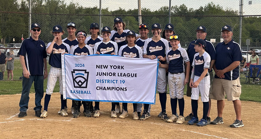 The Pine Bush junior baseball team poses with their District 19 championship flag after beating Town of Newburgh at Pine Bush Town Park.