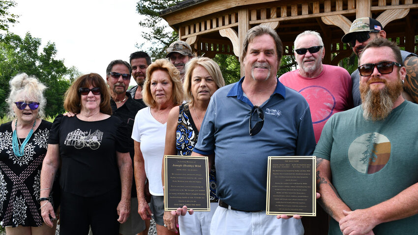 The Wild family in front of Buddy and Alice&rsquo;s gazebo, holding up plaques dedicated to the couple.
