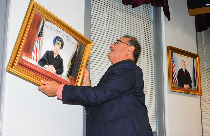 Retired Cornwall Judge Frank Navarra is shown straightening a photo of himself that will hang forevermore in the Town of Cornwall Justice Court.