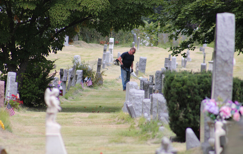 Trimming is done along the headstones in the mid-morning hours.