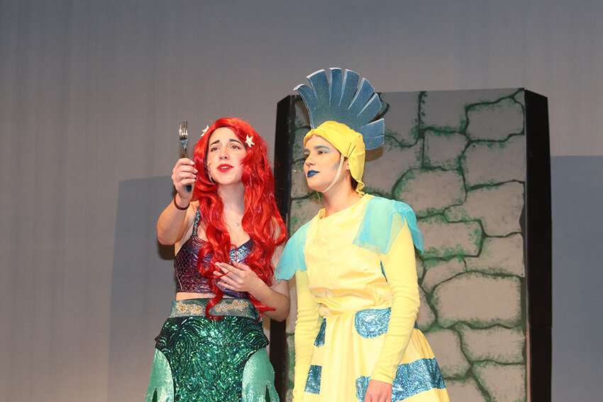 Arial, played by Natalie Terwilliger, and Flounder, played by Heather Masterson, examine a “dinglehopper.”