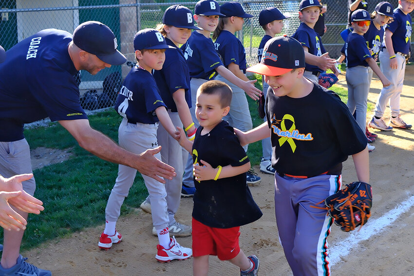 Riley Bell [R] walks with his brother Brady around the baseball diamond to mark his one year of being cancer free.