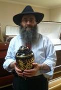 Rabbi Anchelle Perl of Chabad of Mineola, holds an urn during a lecture on the prohibition of cremation.