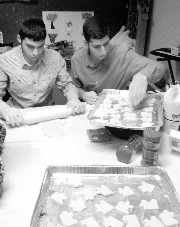 Kulanu students Ralph and Matis baking puzzle cookies that were later sold along with autism puzzle ribbons. Students attached a puzzle label explaining what autism is in front of the Kulanu Center for Special Services.  Puzzle pieces, the symbol adopted by the autism awareness month project.