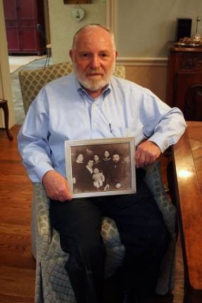 Leibel Zisman, holding a photograph of his family. He and his older brother, Berel, were its only survivors.