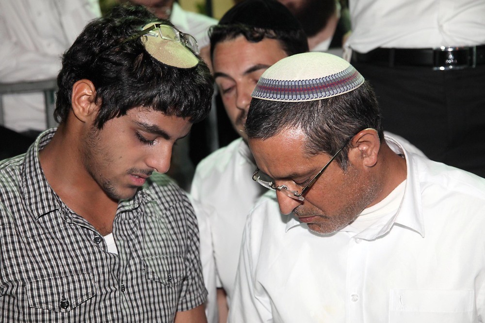 Ouria Yifrach (right), father of missing Israeli teenager Eyal Yifrach, and Eyal's brother Assaf pray alongside hundreds for the safety of Eyal on June 14.