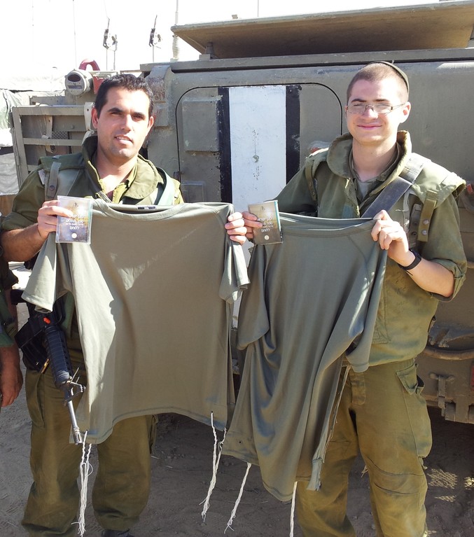 Two Israeli soldiers proudly display their new olive green dri-fit tzitzit and plastic encased siddurim.
