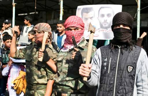 Palestinians in the southern Gaza Strip town of Rafah hold axes and a gun and display images of the killers, as they celebrate the massacre.