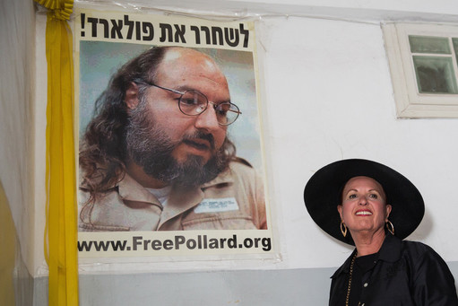 Esther Pollard walks past a poster of her husband before speaking to reporters outside of her Jerusalem home on July 29.