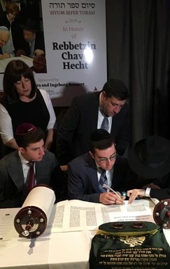 Eli Borochov writes a letter in a Torah, at the 75th anniversary gala of the National Committee for the Furtherance of Jewish Education, in Pier 60, Manhattan.