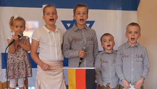 Andreas Boldt's children sing &quot;Adon Olam&quot; against the backdrop of the Israeli and German flags.