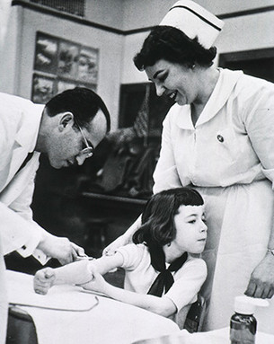 Jonas Salk gives the vaccine to a child as part of a field trial at a Pittsburgh elementary school.