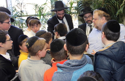 Yanky Brach is greeted by students after the surprise presentation at Yeshiva Darchei Torah. From right: Brach; Rabbi Dovid Frischman, menahel of YDT&rsquo;s middle school; and Rabbi Avrohom Bender, a rebbi and menahel at YDT.