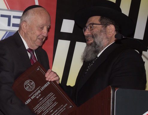 Rabbi Moshe Lerer receives a plaque honoring his service to Hatazalah, from Rabbi Yaakov Bender.