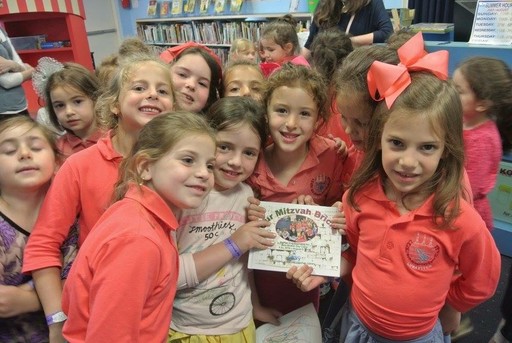 Bais Rivkah Day Camp girls from Brooklyn with a book they wrote and illustrated during a camp trip to the library.