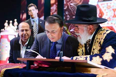 Lev Leviev (center) writing in a Torah scroll with Rabbi Eliyahu Yaakov, right, and Israel&rsquo;s then- defense minister- Moshe Yaalon, in Jerusalem on March 23, 2014.