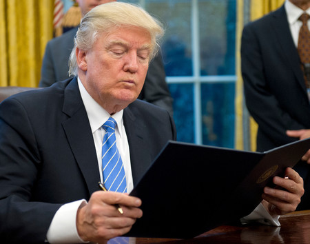 President Donald Trump reading the first of three executive orders he was preparing to sign in the Oval Office on Monday. Action on an embassy move to Jerusalem was not among them.