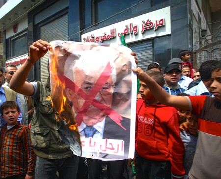 Palestinians burn a crossed poster depicting Palestinian President Mahmoud Abbas, in the southern Gaza Strip on April 14, 2017.