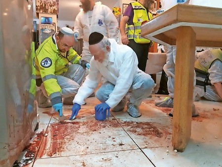 ZAKA volunteers, including its chairman, Yehuda Meshi Zahav (right), clean the scene of Friday night&rsquo;s deadly Palestinian terror attack at the Salomon family home in Halamish.