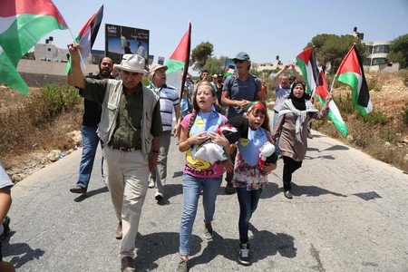 Palestinian demonstrators holding the Palestinian flag protest against the expansion of Jewish settlements in the West Bank village of Nabi Saleh, near Ramallah, on Aug. 7, 2015.