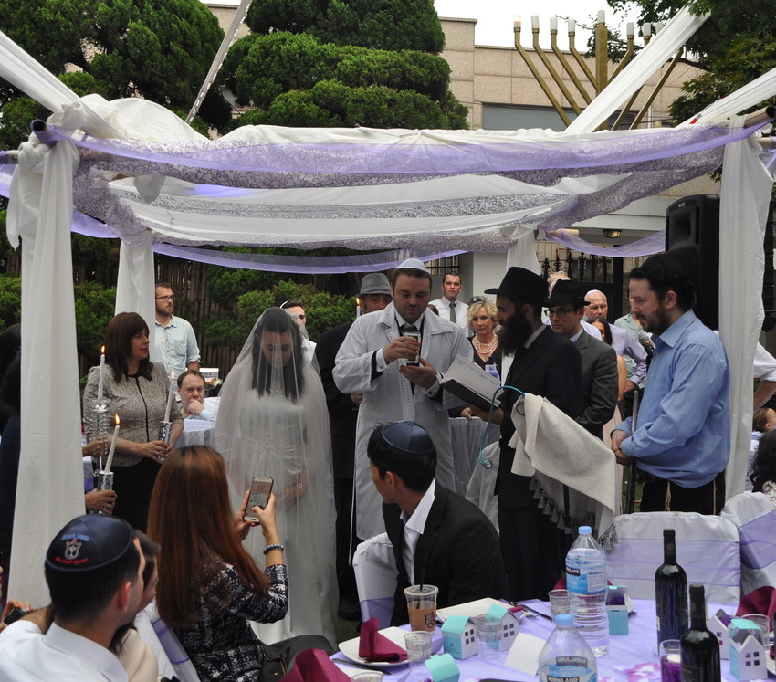 Rabbi Osher Litzman, under chuppah in black, performing a Jewish wedding in Seoul.