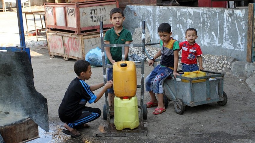 Palestinians fill plastic bottles and jar cans with drinking water from a public tap in the southern Gaza Strip refugee camp of Rafah, on July 26, 2015.