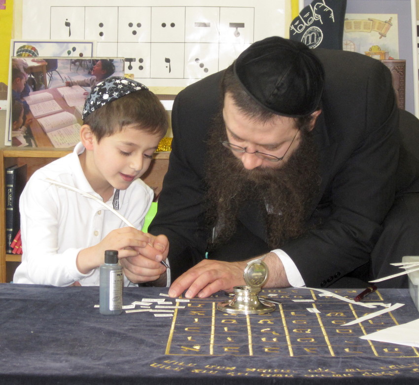 Asher Romer, a Pre-1A student at YOSS, is pictured with the sofer, Rabbi Betzalel Katkovsky.