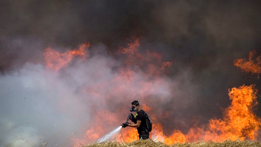 Israeli firefighters extinguish flames in a wheat field caused by kites flown by Palestinians near the Gaza border on May 30.