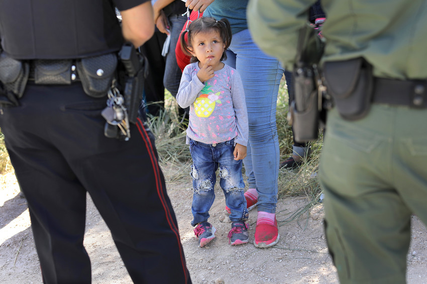 A child is accompanied by officers taking a group of Central American asylum seekers into custody near McAllen, Texas, on June 12.