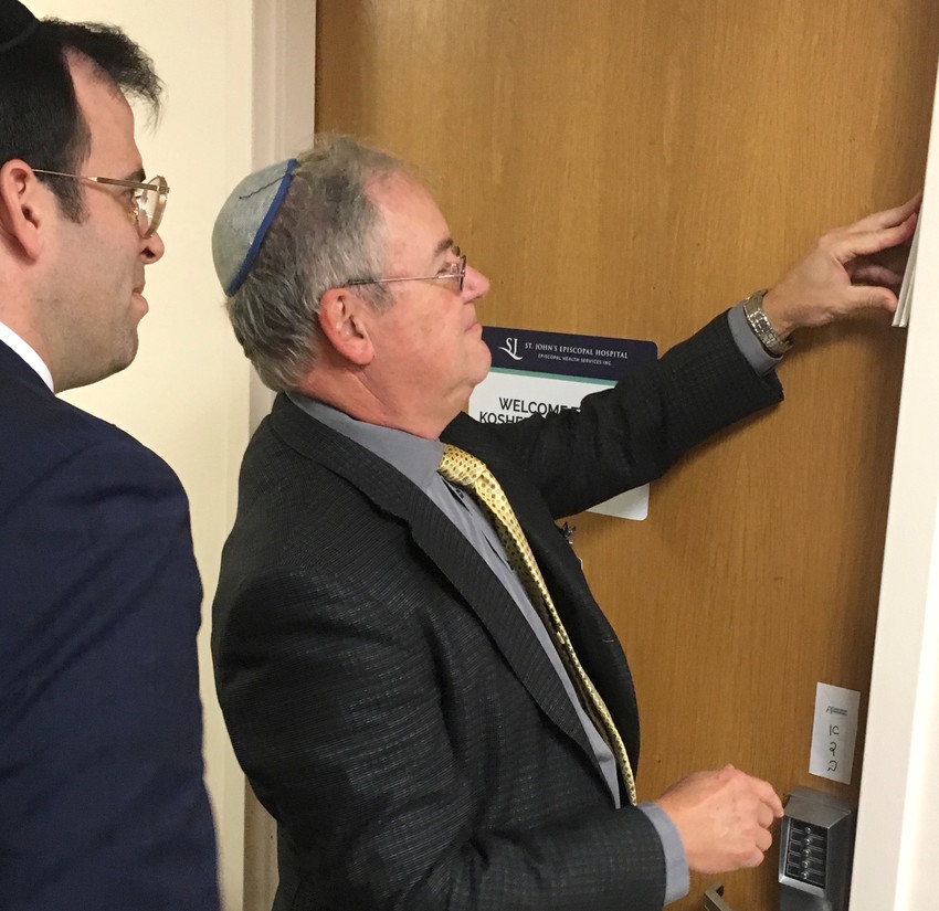 Dr. Nathan Rothman, flanked by Rabbi Boruch Ber Bender of Achiezer, hung the mezuzah.