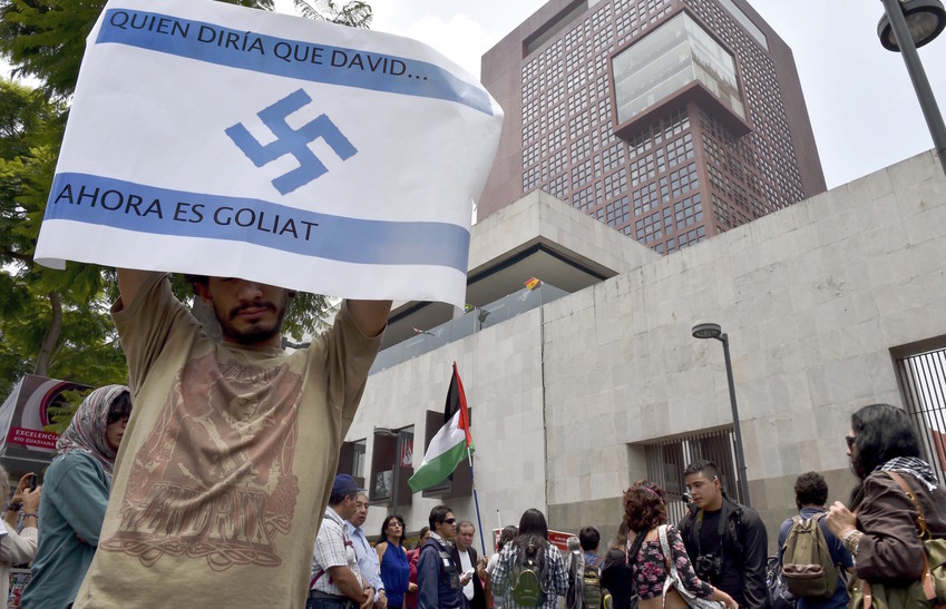 A pro-Palestinian activist holds an Israeli flag painted with a Nazi swastika and the sentence &quot;Who would say that David &hellip; now is Goliath!&quot; during a rally against the Israeli military offensive in the Gaza strip outside the Mexican Foreign Ministry building in Mexico City on July 11, 2014.