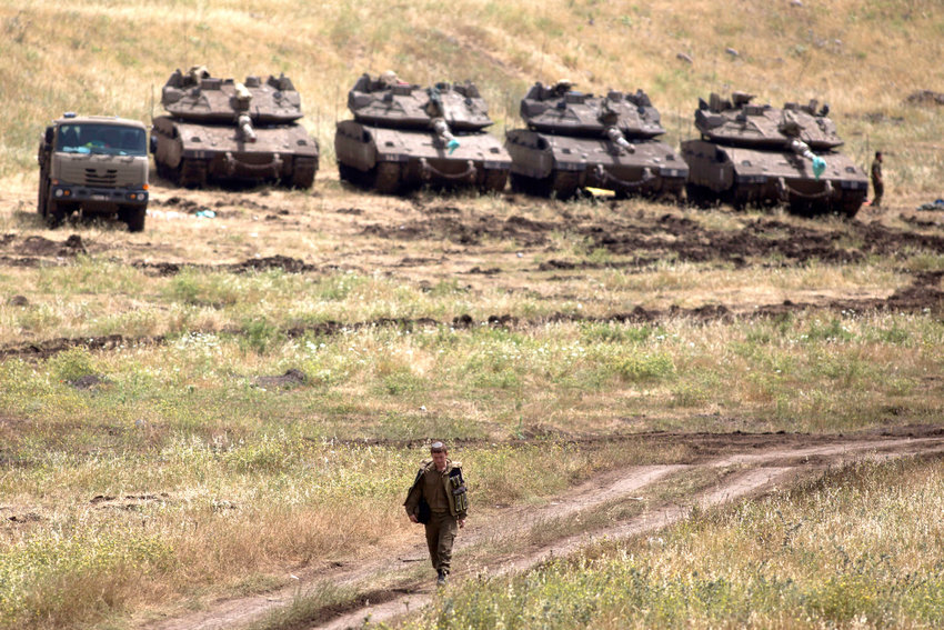 An Israeli soldier walks next to Merkava tanks deployed near the Israeli-Syrian border on May 10, 2018 in the Israeli-annexed Golan Heights.