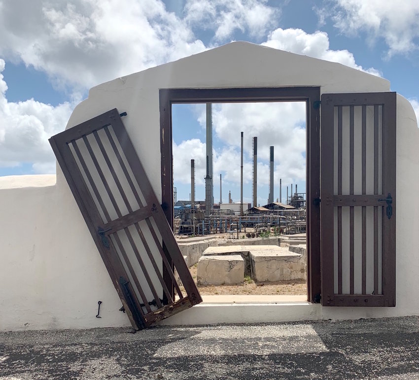 An oil refinery is visible through an entrance too Beth Haim Cemetery in Curacao.