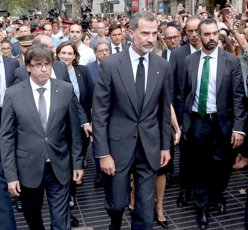 King Felipe VI of Spain (center), accompanied by Catalonia President Carles Puigdemont (left) and Barcelona Mayor Ada Colau, prepares to lay a wreath at the site of a truck-ramming attack two days earlier on La Rambla that left two people dead and more than 100 wounded.