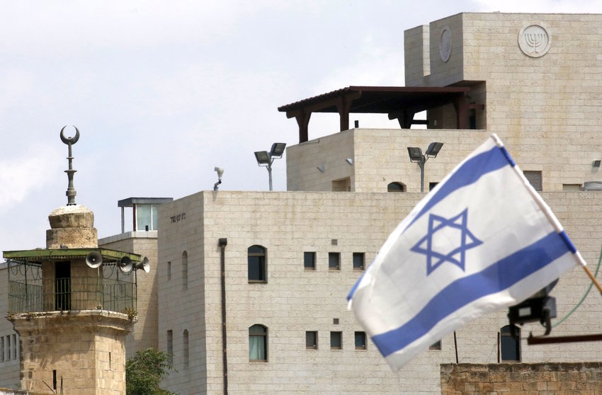 An Israeli flag in the small Hebron Jewish community, near the minaret of a mosque.