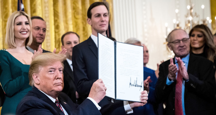 President Trump displays the executive order after signing it on Dec. 12. He is flanked by his daughter Ivanka and son-in-law Jared Kushner. At right is attorney Alan Dershowitz.