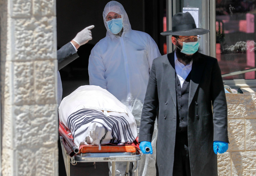 An Israeli rabbi walks alongside the body of Eliahu Bakshi-Doron, the former Sephardic chief rabbi of Israel, who died from complications of the coronavirus.