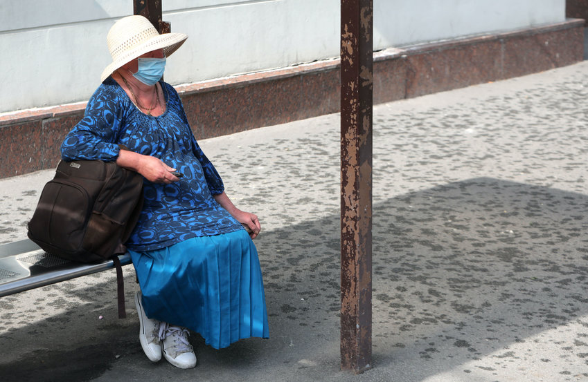 An elderly woman sits at a stop of public transport, Kyiv, capital of Ukraine.