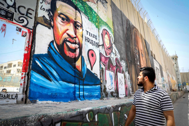 Palestinians walk past a graffiti of George Floyd painted on a section of the separation wall in Bethlehem, on June 8.