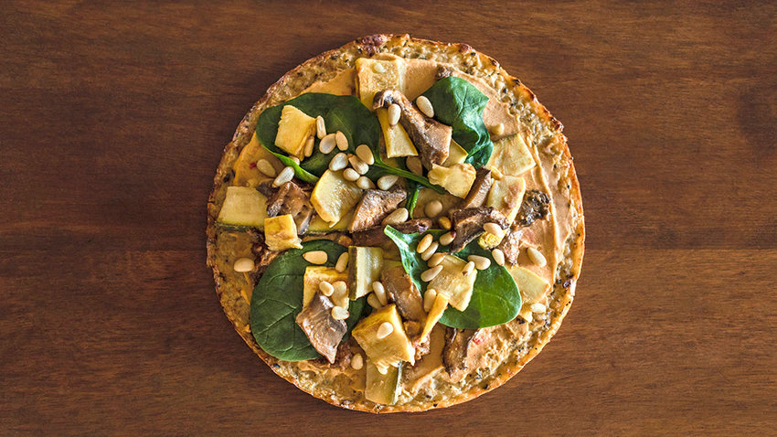 A beautiful vegan pizza rests on a rustic wooden table.