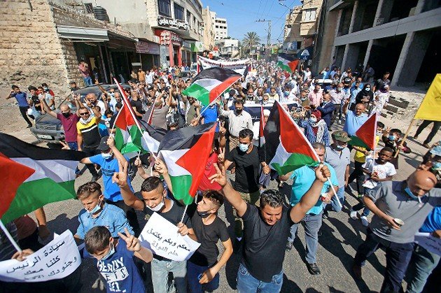 Palestinians hold flags during a rally in support of Palestinian Authority leader Mahmoud Abbas in Tubas on Sept. 27, 2020.