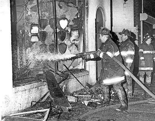 Firefighters use a hose to tackle the blaze through the front window of The Riverdale Press' storefront office on Broadway.