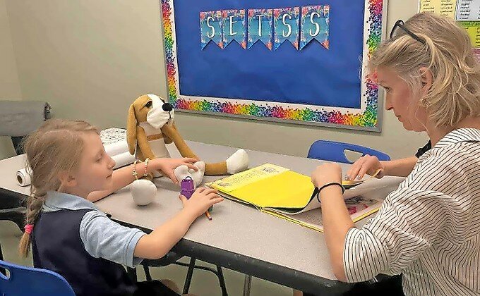 Inna Muntyan, an educational interventionist at Hebrew Language Academy in Brooklyn, works with Polina, a refugee from Ukraine, with a Hibuki therapy doll.