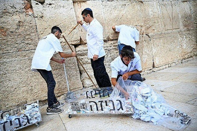 Workers cleaning out the kotel walls by removing all of the notes people placed.