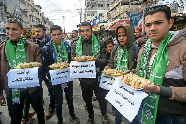 Palestinian supporters of Hamas pass out sweets in Rafah in the southern Gaza Strip on March 17, 2019, after a terrorist attack in which a Palestinian man killed a 19-year-old IDF soldier, stole his weapon and used it to shoot two others near Ariel, in the West Bank.